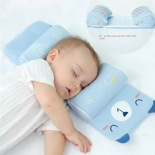 Baby sleeping on a blue pillow with cartoon designs on a white background