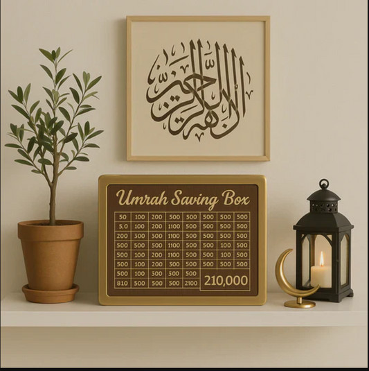 Umrah saving box with Arabic calligraphy on a wall, potted plant, and candle lantern in the background.