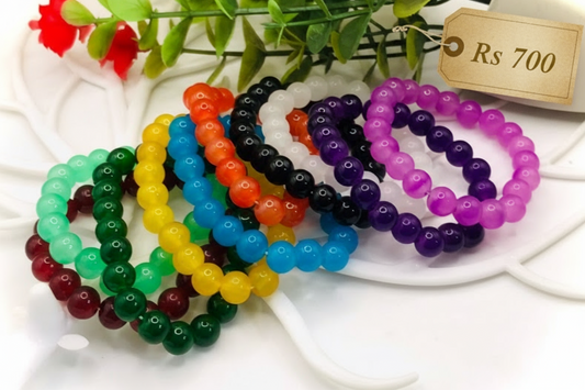 Colorful beaded bracelets on a white surface with a price tag.