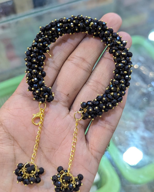 Black beaded bracelet and earrings on a hand with a blurred background