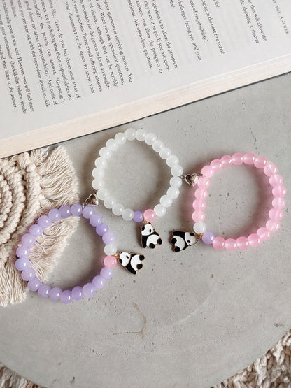 Three beaded bracelets with panda charms on a textured surface.