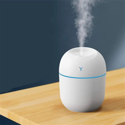 White humidifier with blue accents on a wooden surface against a dark background